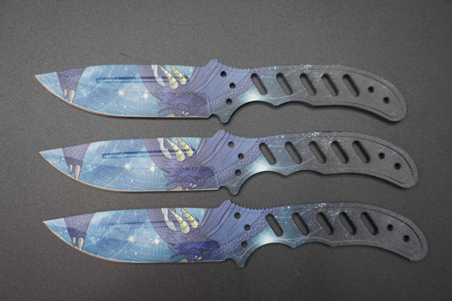 Three knives with blue and purple handles and blades on a dark gray background