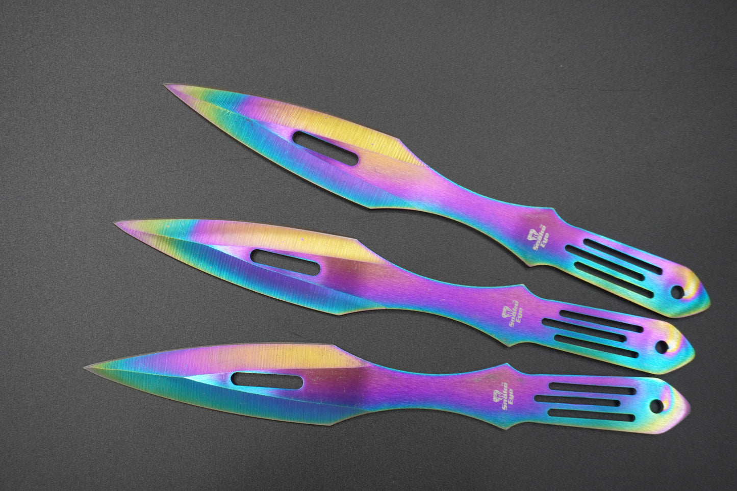 Three colorful throwing knives on a gray background