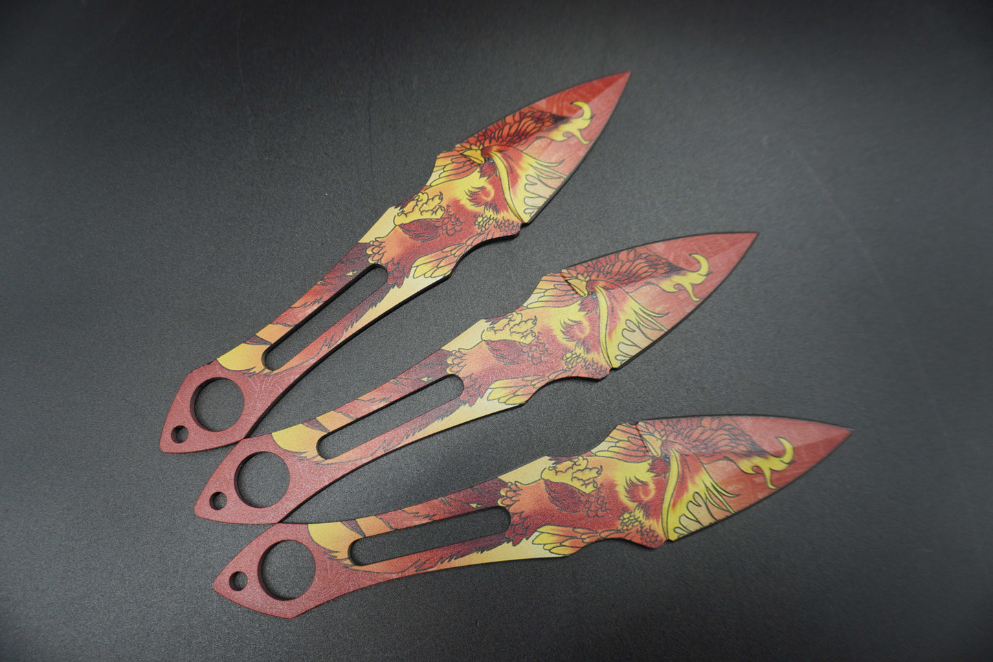Three decorative knives with floral patterns on a dark background