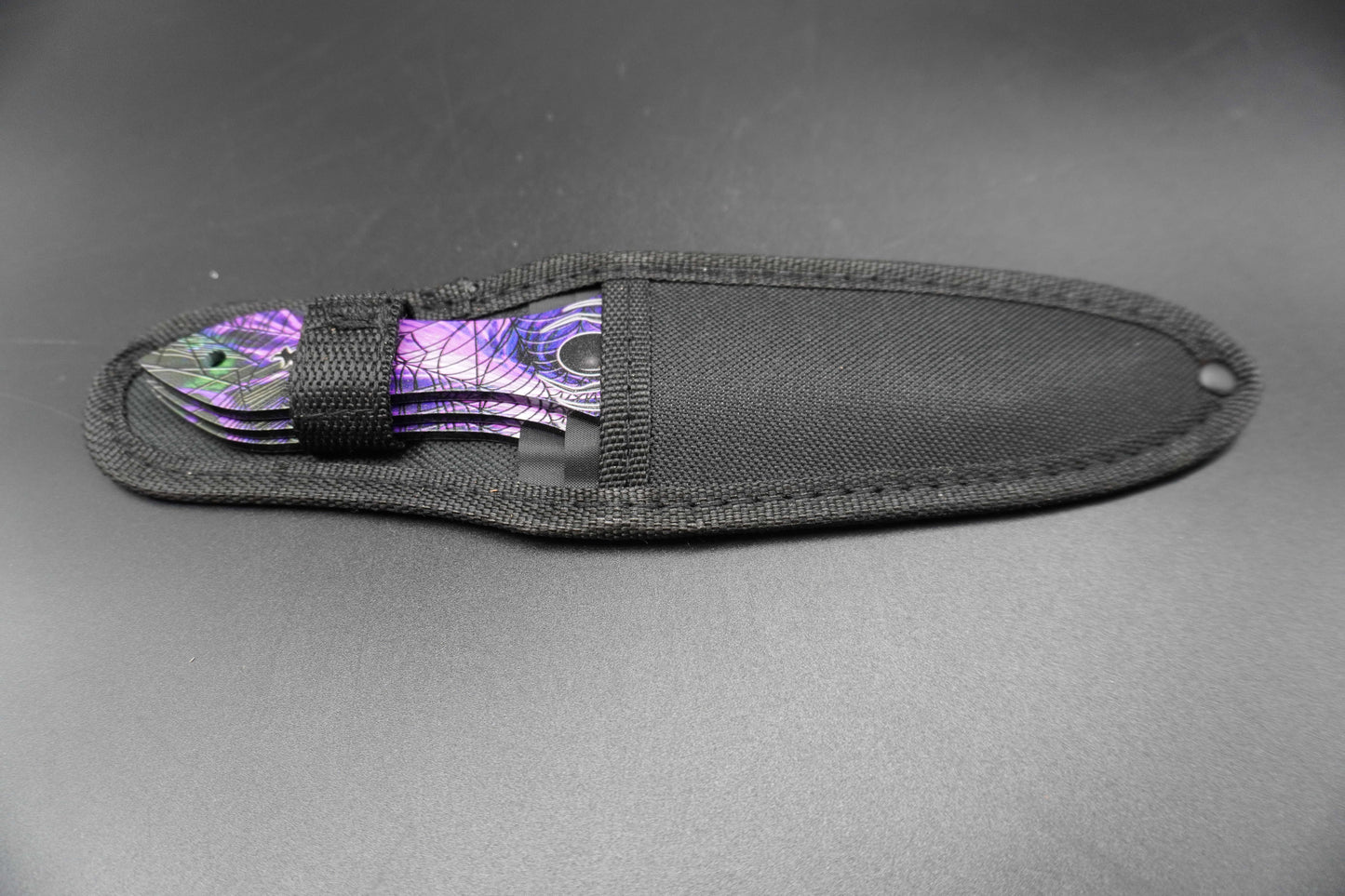 Fishing lure with purple and green design inside a black sheath on a gray background