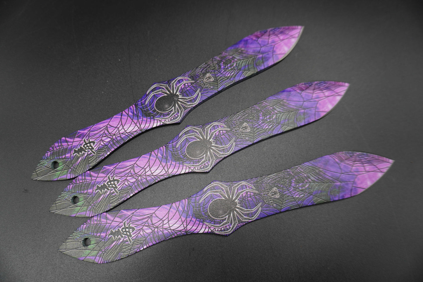 Three purple decorative items with intricate patterns on a dark surface