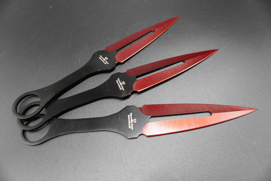 Three black and red throwing knives on a gray background