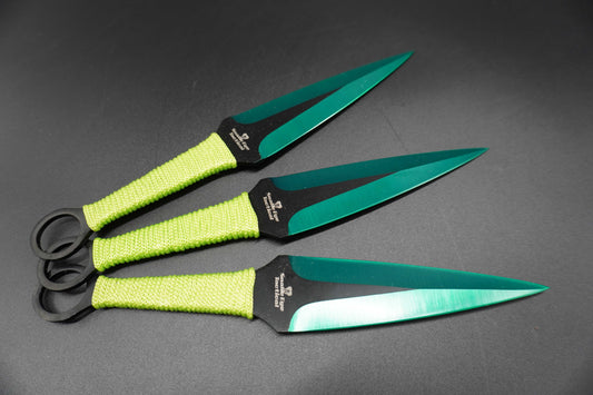 Three throwing knives with green blades and black handles on a gray background