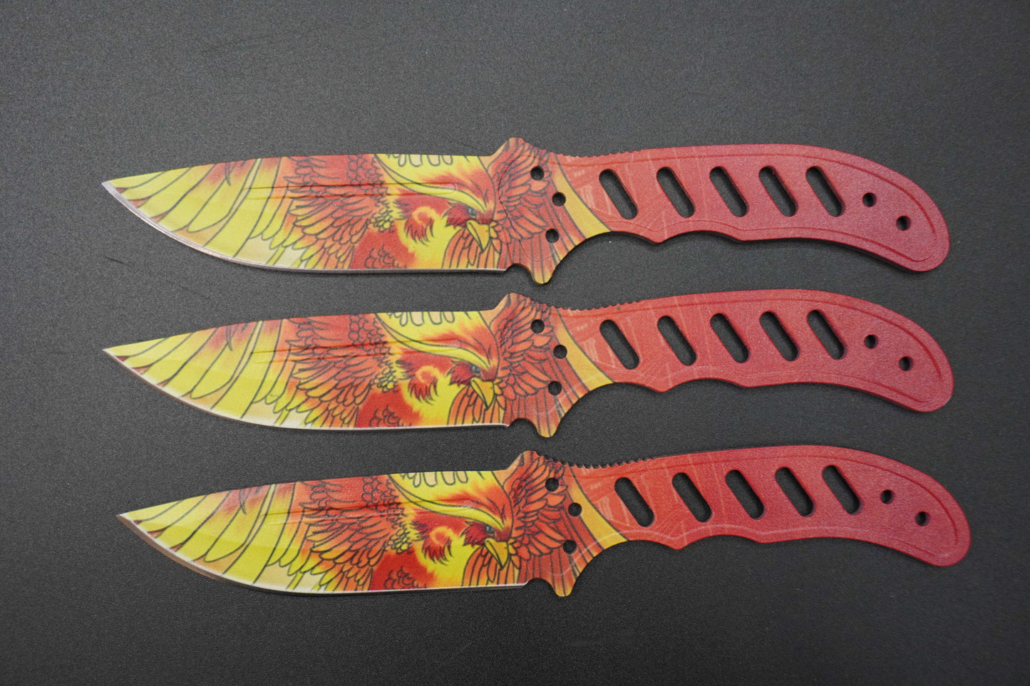Three knives with colorful blade designs and red handles on a black background