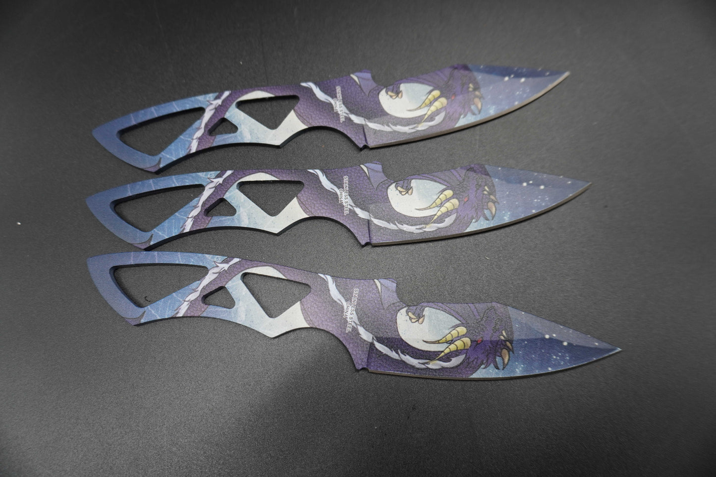 Three decorative blades with artistic designs on a dark surface