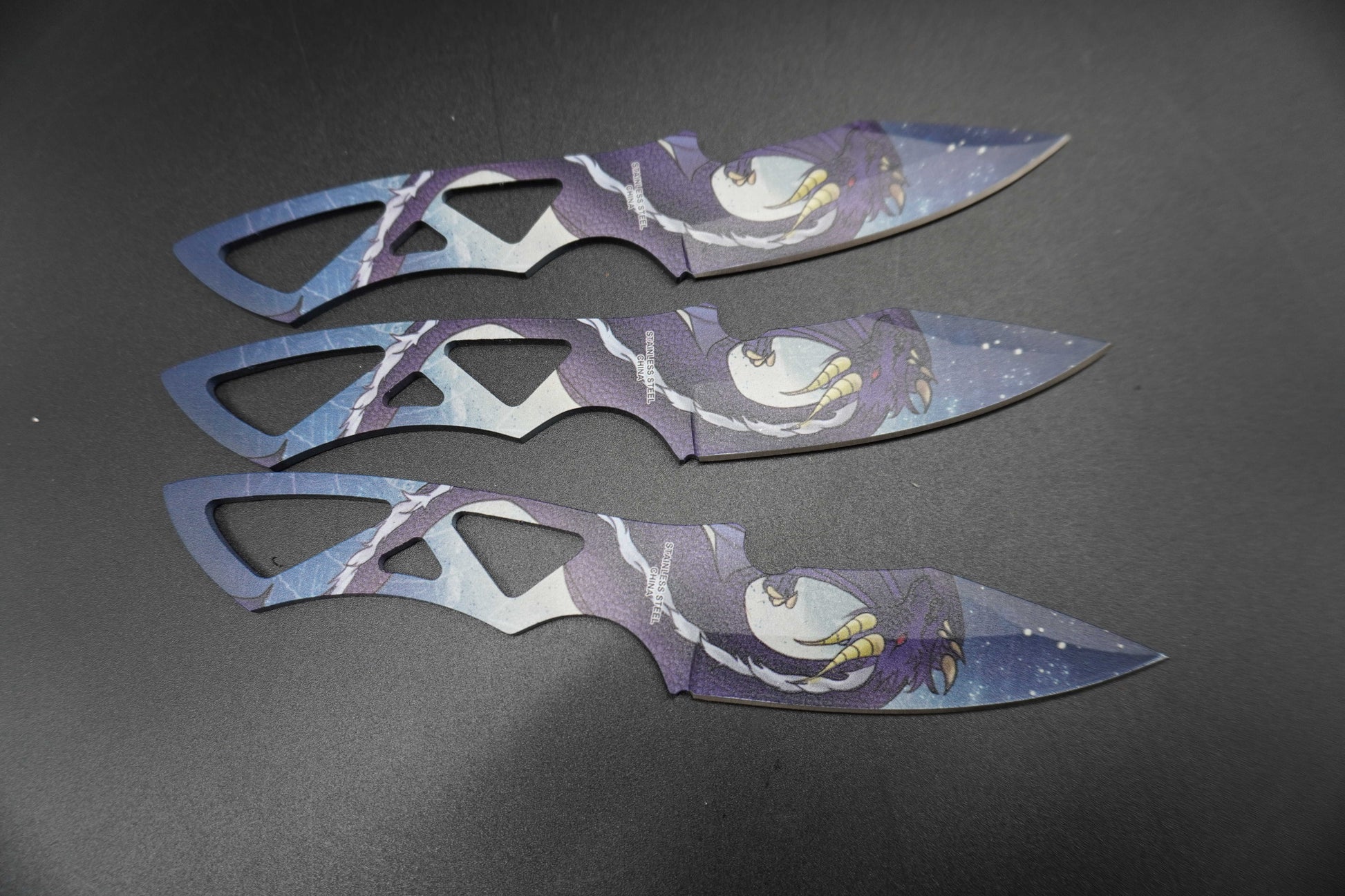 Three decorative blades with artistic designs on a dark surface