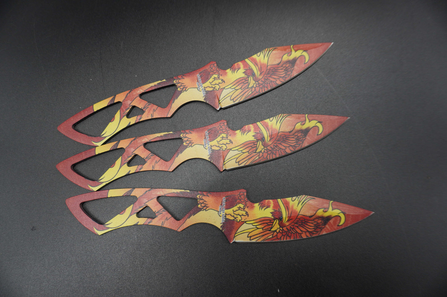 Three decorative knives with floral patterns on a dark background