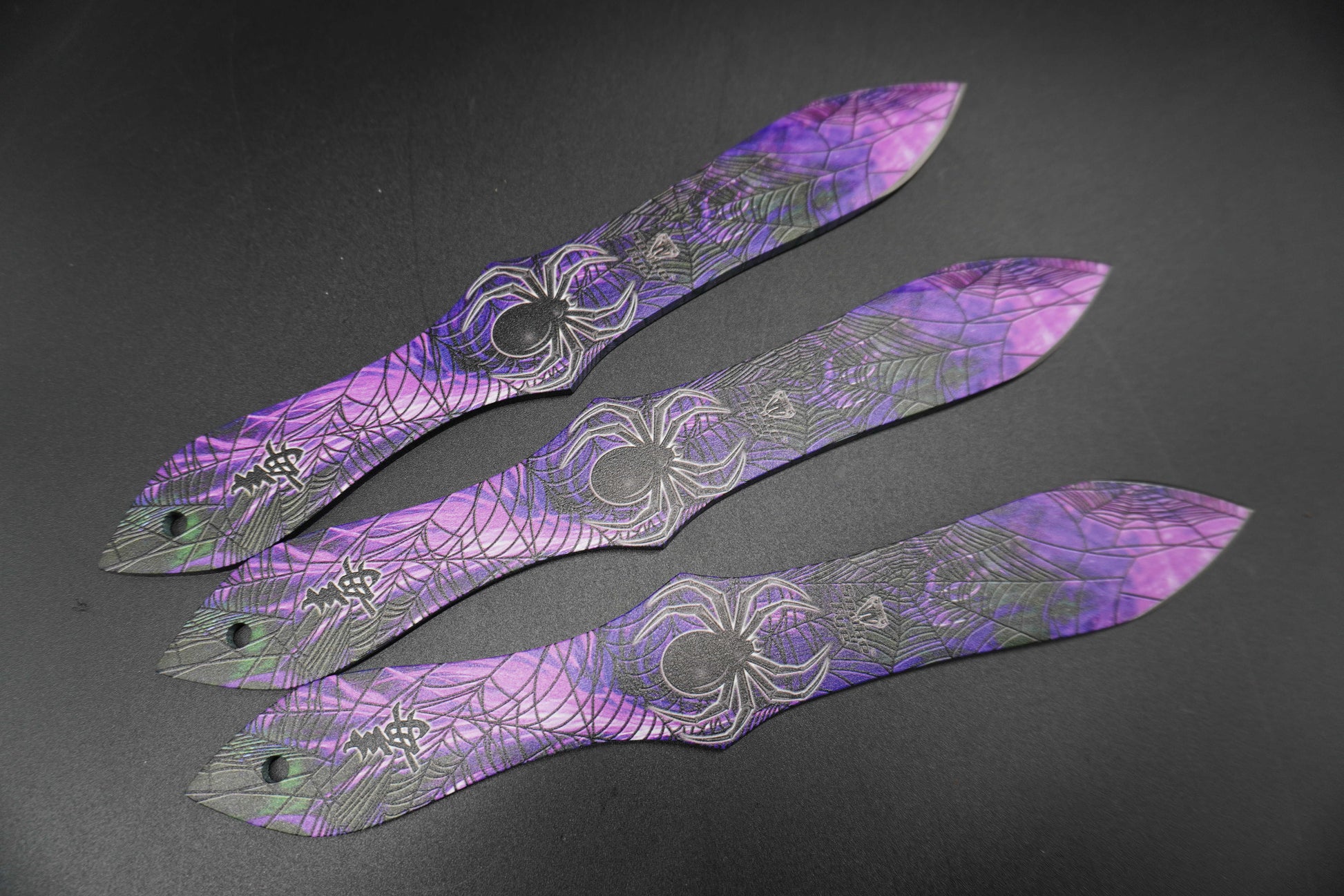 Three purple decorative items with intricate patterns on a dark surface